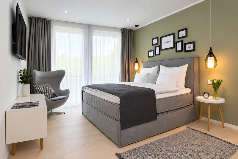 Schlafzimmer mit Boxspringbett und grüner Wand